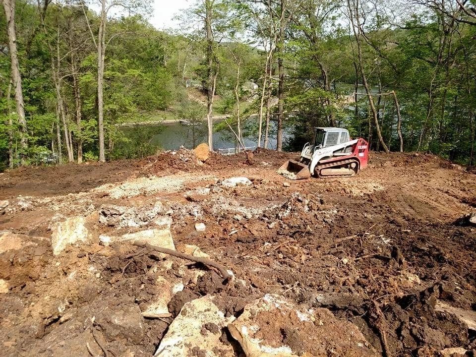 A tractor is parked on the dirt near some trees.